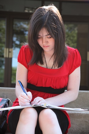 Homeschool girl in red dress reading outside in sunshine