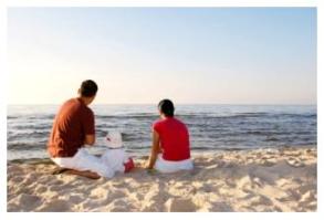 Couple with small child on beach looking out over the water